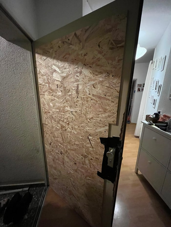Provisorisch mit Holzplatte abgesicherte Tür nach Einbruchschaden