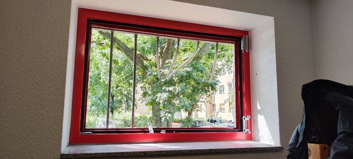 Geöffnete Fenstersicherung an einem roten Fenster